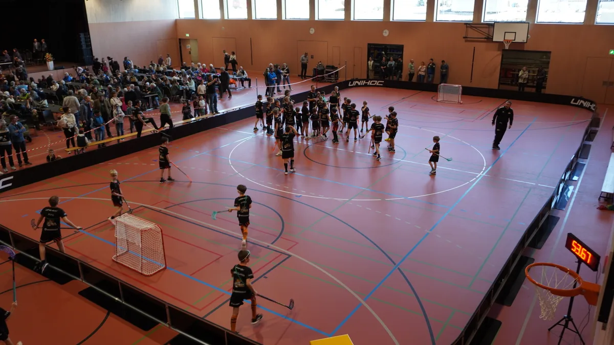 In einer Mehrzwekchhalle wird Unihockey gespielt.